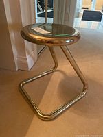 Side-angle view showing stool's cantilever tubular metal base and circular seat.
