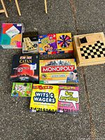 Photo of all games laid out on a surface showing the variety of game boxes including Star Trek Catan, Monopoly Electronic Banking, Bean Boozled with spinner, Say Anything, and Wits & Wagers among others.