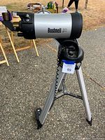 Side view of Bushnell North Star GOTO reflector telescope mounted on silver aluminum tripod with wired hand controller.