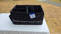 Black foldable car trunk organizer with 3 adjustable compartments visible from the top. Reflective strips on exterior pockets.
