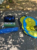 All camping and water recreation items arranged on asphalt for inventory and display.