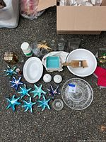 Photo showing assortment of household items including glass starfish decorations, plates, bowls, and jars