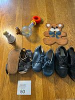 Shows toddler shoes, baby toys, and wooden decorative items arranged on a wooden floor