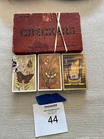 Top view of vintage checkers box with three sealed decks of playing cards placed in front.