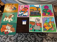 All seven vintage wooden puzzles displayed on a table, showing the front artwork of each.