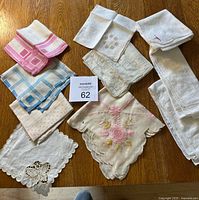 Top view of about 10 vintage handkerchiefs spread out on wooden surface, showing various trims, embroidery, and patterns.