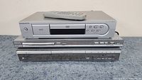 Stack of three DVD players: Magnavox MDV-430 on top with remote, Philips DVP5960 in middle, Zenith DVB216 on bottom