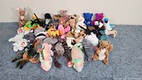 Overall photo showing all 33 Beanie Babies plush toys arranged in a pile on blue surface.