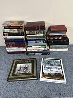 Three stacks of various history, war, and travel hardcover and paperback books, showing titles related to Vietnam War, ancient civilizations, and international history.