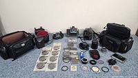 Full overhead view of all included items showing cameras, filters, lenses, bags, binoculars, and accessories arranged on table.