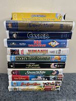 Stacked VHS tapes showing spines with titles including Care Bears, The Sound of Music, Casper, 101 Dalmatians, Jumanji, Pooh's Grand Adventure, The Nightmare Before Christmas, Snow White, Shaggy D.A., See Spot Run, The Wizard of Oz.