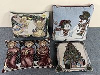 Four Christmas pillows arranged showing different holiday-themed designs including angels, snowmen, carolers, and Christmas tree.