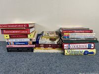 Photo of stacked cookbooks showing titles and authors related to family and traditional cooking.