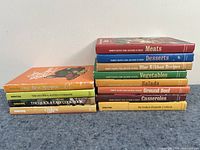 Stack of 12 Southern cooking-themed cookbooks showing vibrant colored spines with titles such as Meats, Desserts, and Vegetables.