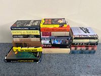 Photo showing three stacks of hardcover books from the fiction lot with various titles visible, including The Phantom of the Opera and The Third Wave.