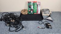 Photo showing various garage items including extension cord, coiled rope, black tray, flexible hose/cable and two valve kits in packaging.