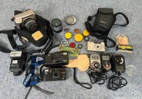 Wide top-down shot showing entire photography lot with cameras, lenses, filters, flash units, light meters and cases