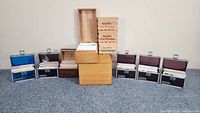 Front view of all recipe boxes, wooden boxes, and empty wooden crates arranged in a row on a gray surface