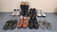 All eight pairs of shoes including sneakers, boots, dress shoes, and sandals in a single photo showing their overall condition and style.