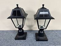 Photo showing both solar outdoor lamps side by side with a beige background, highlighting their design and condition.