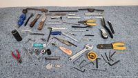 Full view of the collection of 71 assorted hand tools arranged on a carpeted surface showing the variety of sizes and tool types.