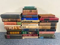 Large stack of vintage hardcover books arranged in rows, showing different titles and wear.