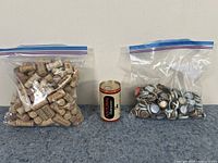Two ziplock bags on a white surface; one containing a large number of wine corks, the other containing assorted bottle caps, with a vintage National Bohemian beer can placed in front between them.