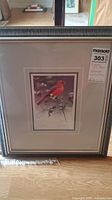 Framed print showing the full artwork of a cardinal bird among snowberries with visible frame and matting.