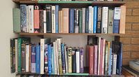Wide view of a shelf densely packed with approx. 30 assorted war-related books of various sizes, covers mostly hardcover with dust jackets.
