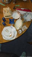 Flat lay of all china items and candles on wooden table, showing plates, bowls, cheese dish, candles, candle holders, and snuffer
