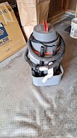 Shop-Vac QSP wet/dry vacuum with coiled hose and attachments on a grey floor.