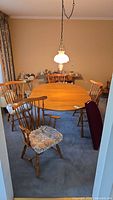 Dining area showing the Vilas maple drop leaf table surrounded by four chairs with floral cushions under a hanging lamp.