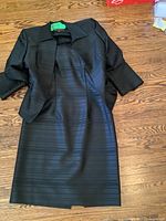 Full view of black dress with matching jacket laid flat on wooden floor