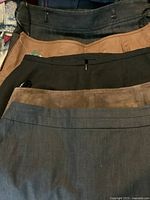 Photo showing 5 skirts stacked, colors from top black, tan, black, brown suede, blue-grey.
