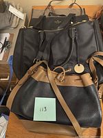 Four handbags arranged on a table showing mixed colors and various handle styles, highlighting the lot contents.