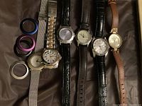 Six ladies wristwatches laid out on fabric background showing different band materials and watch face designs.
