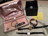 Group photo of 7 ladies watches including one in a pink velvet lined box and another in a black box