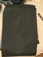 Folded black men’s dress pants with a clean flat front and single back welt pocket.
