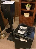 Black Energy e:XL speakers on stands, amplifier, subwoofer and cables on floor, near furniture.