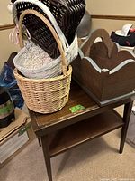 Top angled view of dark wood side table surface, baskets stacked on top, and wooden storage bin beside it