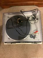 Top view of turntable with dust cover closed, showing overall condition and included cables.