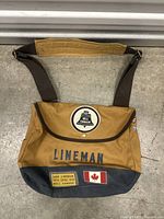 Front view of the Bell Canada vintage lineman canvas shoulder bag showing Bell Canada logo patch, LINEMAN stencil, Canadian flag patch, and technical specification patch.