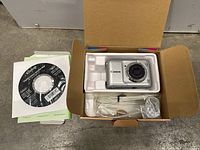 Photo showing Canon PowerShot WP camera in packaging with USB cable, AC adapter, and software CD.