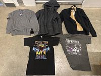 Lot showing all 5 clothing items laid out on floor: gray Tommy Hilfiger sweater with tag, black quilted hooded jacket, black and tan zip-up jacket, black Led Zeppelin band T-shirt, gray Jimi Hendrix band T-shirt.