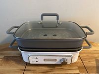Photo of Cuisinart electric grill showing the full unit with glass lid on top on a wooden surface.