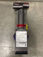 Top view of motorized brush head attached to the cordless vacuum with visible labels and red release latch.