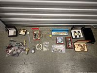 Overview of all jewelry items on concrete floor, including watches, bracelets and necklaces in boxes and loose.