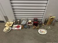 Wide shot of all kitchenware items in lot including plates, ceramic teapot, French press, thermos, glass jug, and small accessories