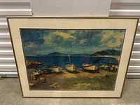 Framed painting showing boats on a shore with sky and water background in impressionist style.