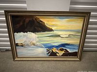 Frontal view of the large oil painting depicting a coastal seascape with waves and cliffs, framed in muted brown and gold frame.